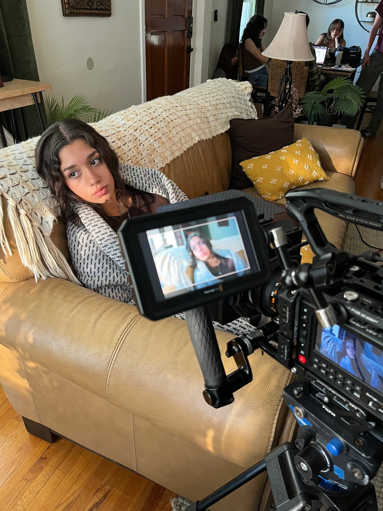 Emily Loaiza wrapped in a blanket on set beside a camera monitor