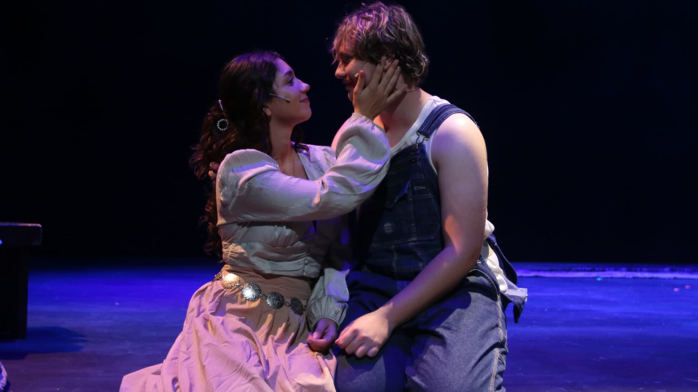 Emily Loaiza cupping a scene partner’s face on stage