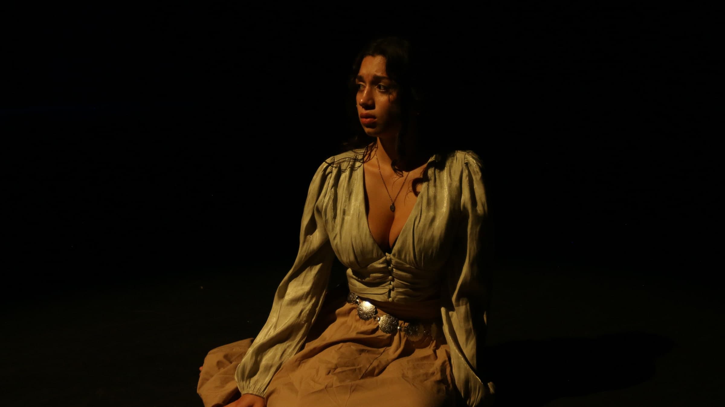 Emily Loaiza seated and tearful under warm stage light