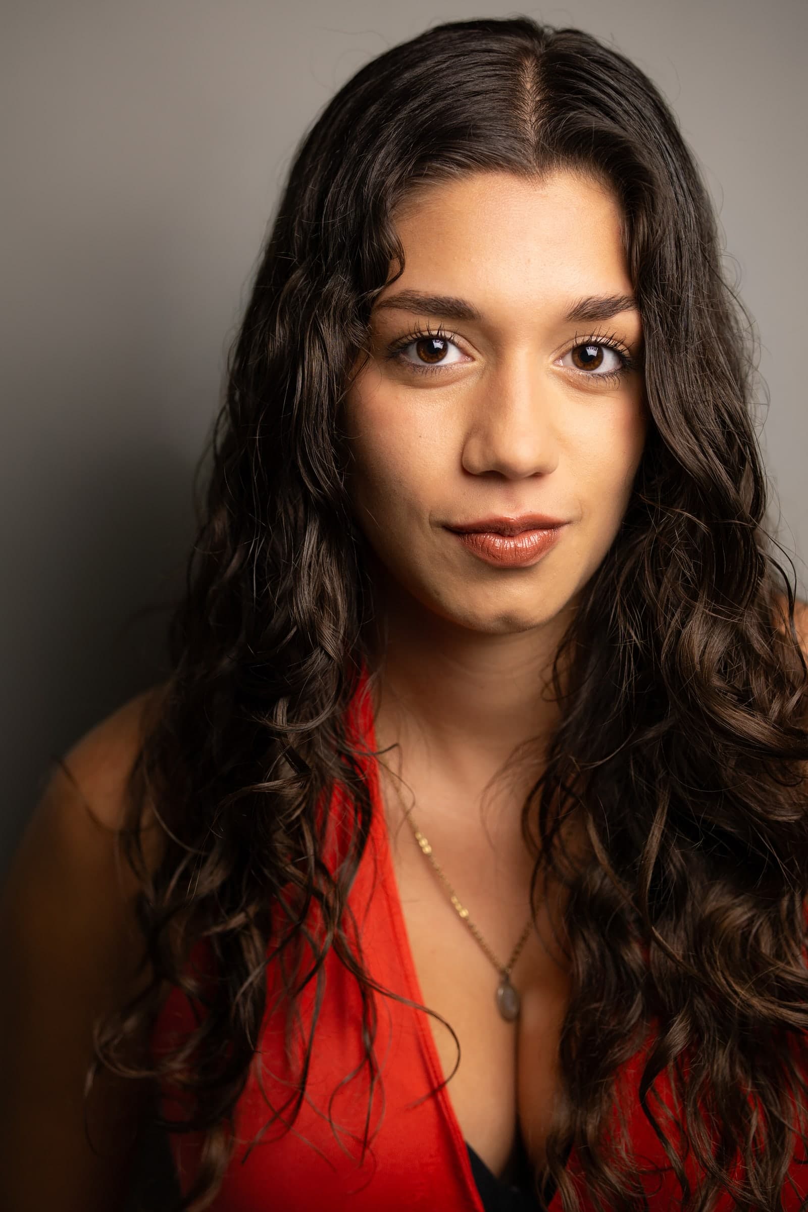 Headshot of Emily Loaiza in a red top against a grey backdrop