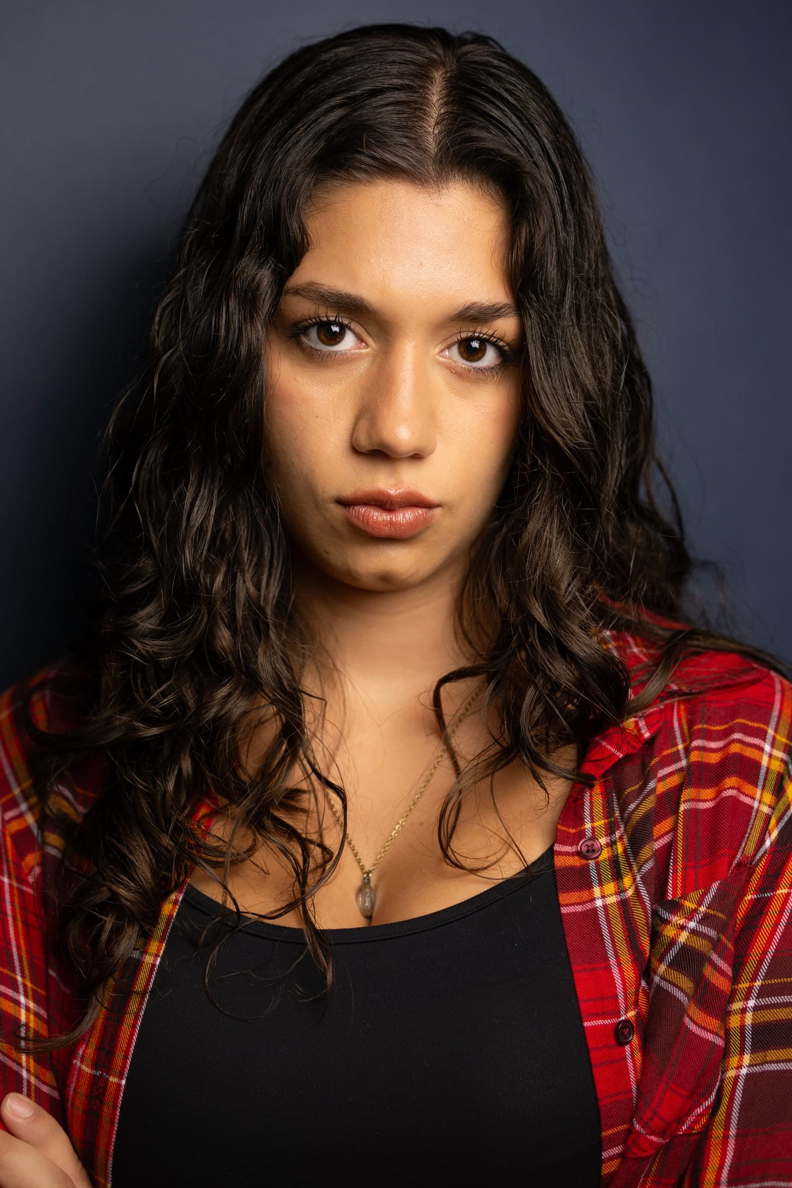 Headshot of Emily Loaiza in a plaid shirt against a navy backdrop