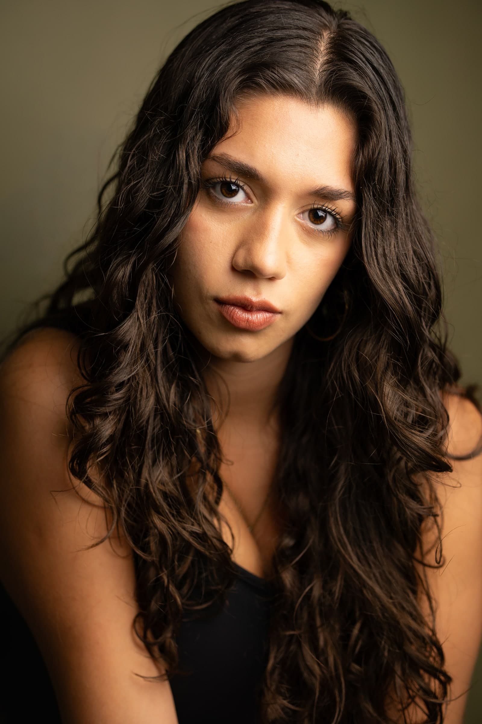 Headshot of Emily Loaiza against an olive backdrop